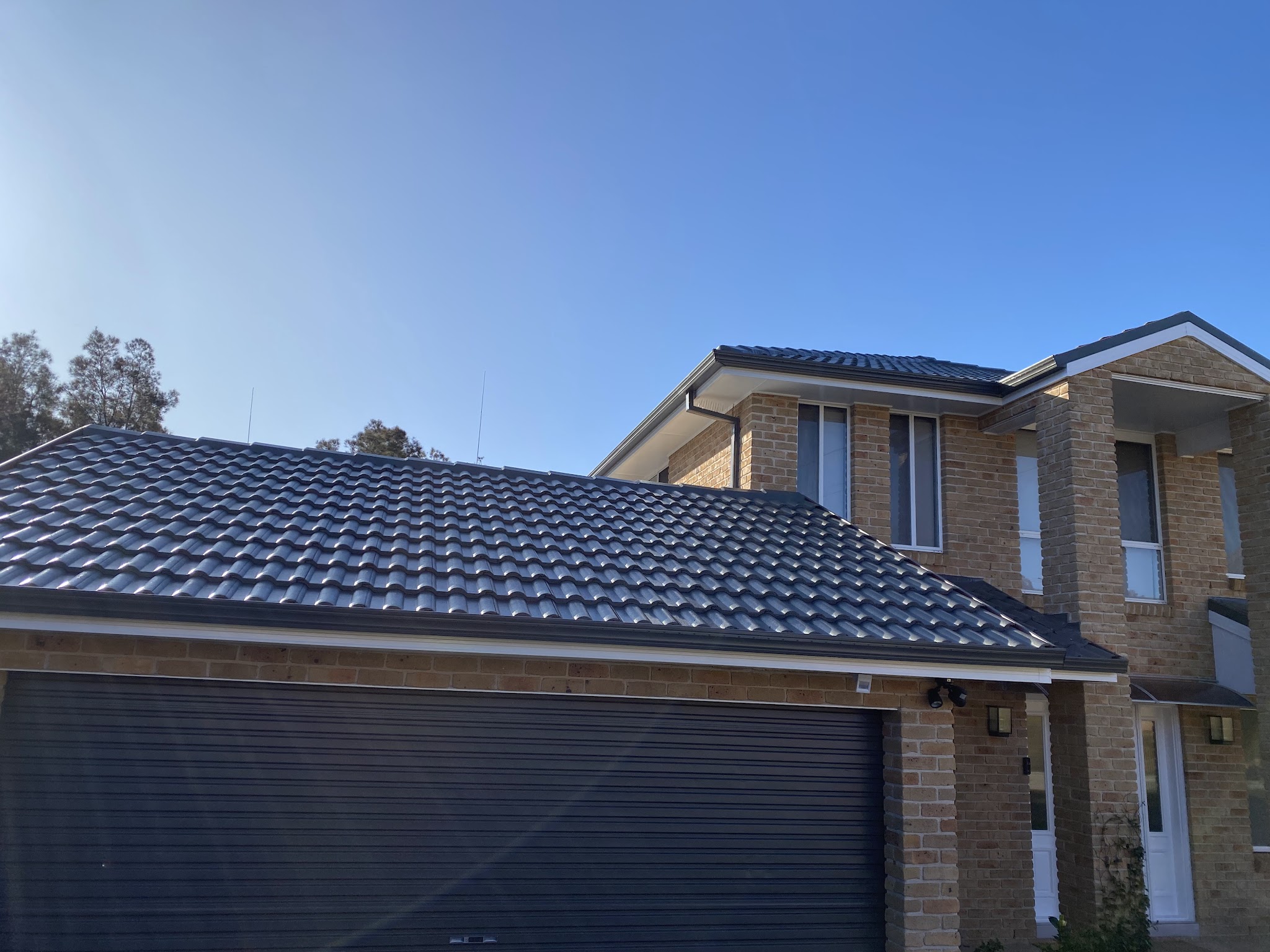 Two-storey brick home with a freshly finished dark grey tile roof over the garage