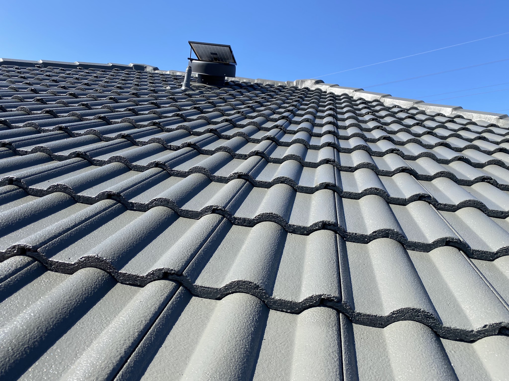 Coated tile roof with a new roof ventilator near the ridge