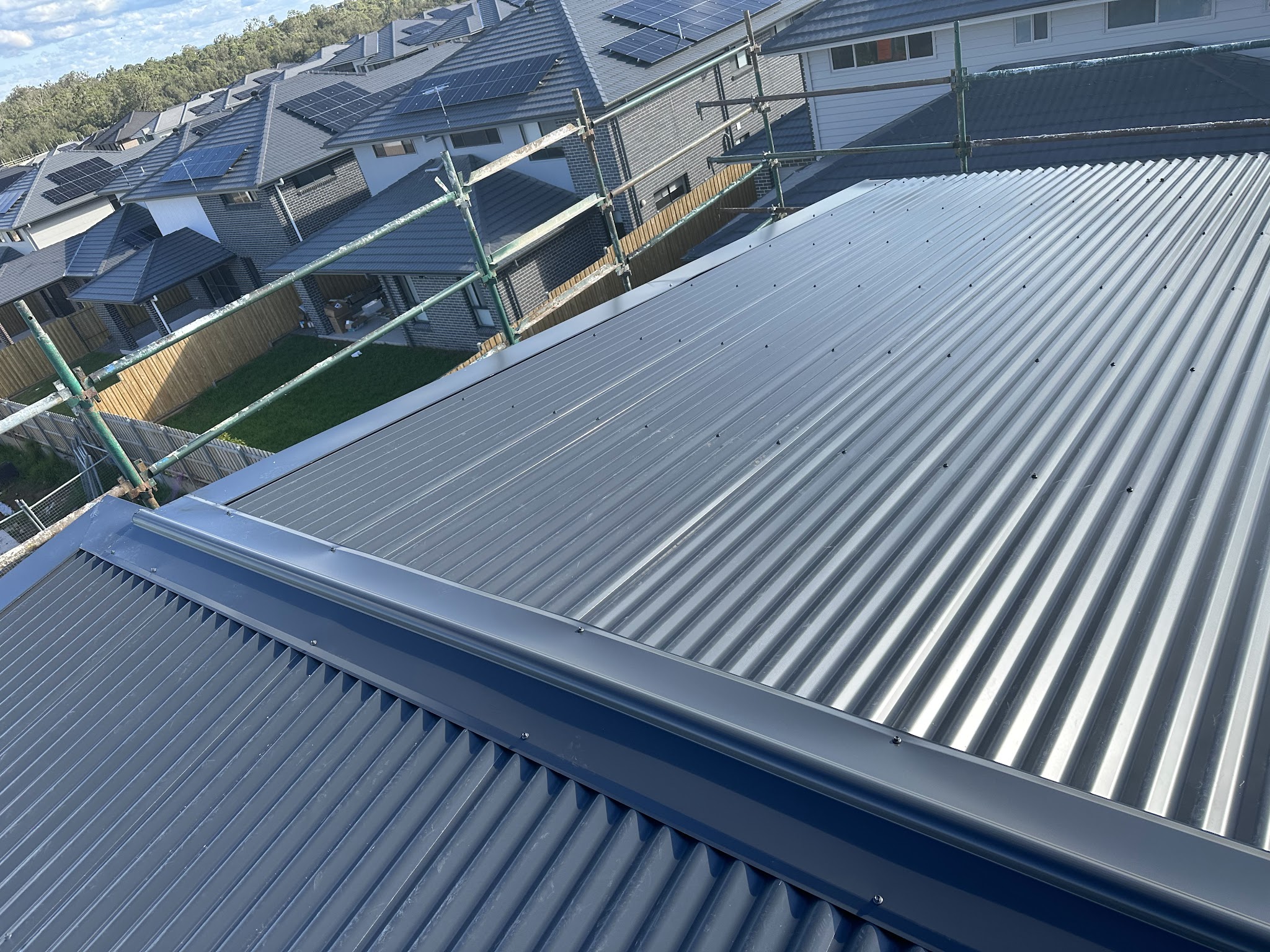Corrugated metal roof with a dark ridge cap and flashing on a new-estate home